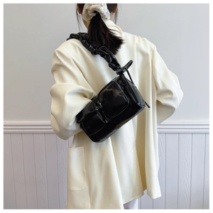 Detail of black glossy PU shoulder bag featuring dual square pockets and ruched strap design