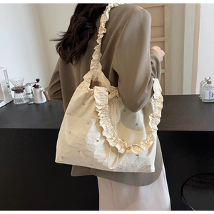 Chic beige tote bag with ruffled edges and silver rhinestones in a cafe lifestyle setting