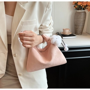 Detailed close-up of pink crescent handbag with fuzzy white flower charm and chain detail