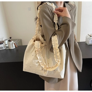 Elegant cream fabric tote bag featuring ruffle trim and silver rivet accents for daily wear