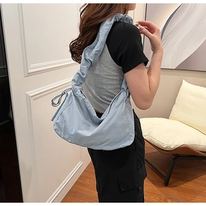 Detail of light blue nylon crossbody bag with ruffled strap and bow decoration