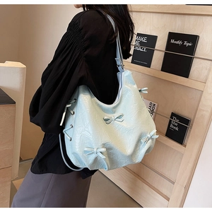 Detail of light blue wrinkled faux leather tote bag with bow and side lacing accents