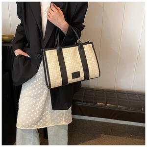 Detail shot of the straw woven tote bag with premium black leather trim and handles