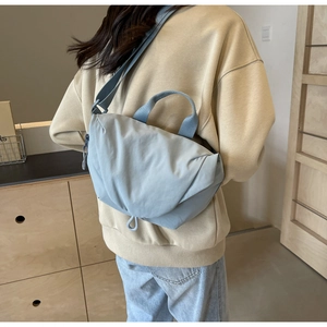 Detail of light blue nylon crossbody bag with adjustable strap and top handle design