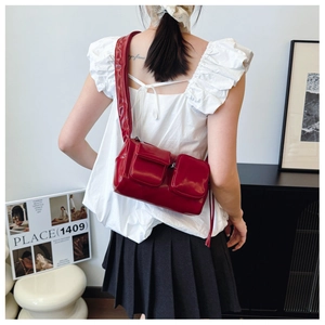 Close-up of glossy red PU leather shoulder bag featuring double flap pockets and wide strap