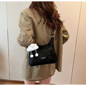 Detail of black PU crossbody bag featuring a plush white cloud charm on khaki blazer