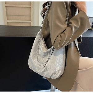 Detail of silver metallic textured PU leather tote bag with chain strap detail on model