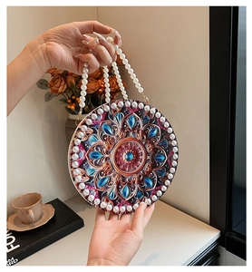 Detail of round handbag with mandala floral print and white pearl beaded strap