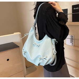 Detail of light blue pleated PU leather bag with cute ribbon bows in a home setting