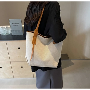 Detail of minimalist canvas tote bag featuring brown leather handles and ivory texture