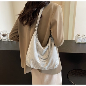 Detail of metallic silver tote bag with pleated texture and stylish silver chain strap