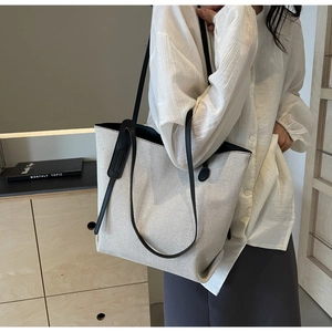 Minimalist canvas tote bag with black leather straps styled on a model in a modern room