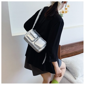 Silver metallic PU shoulder bag with dual front pockets shown in a modern lifestyle setting