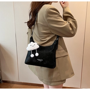 Detail of black crescent faux leather bag with a cute white cloud plush charm pendant