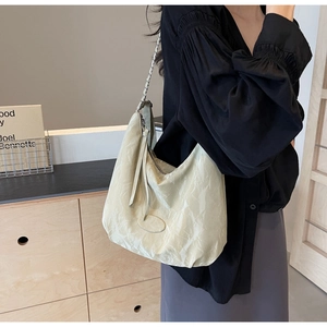 Detail of cream white PU leather crossbody bag with pleated texture and silver chain strap