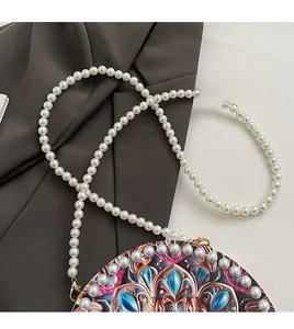 Close-up of baroque patterned crossbody bag with pearl trim and beaded pearl strap