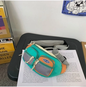 Sac bandoulière en nylon vert d'eau et orange avec design multi-poches sur livre