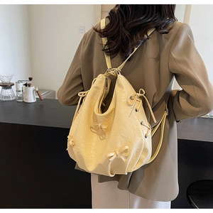 Detail of light yellow drawstring backpack with ruffled texture and bow accents on back