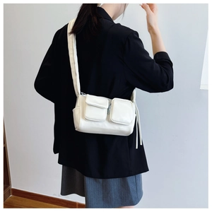 Detail view of stylish cream-white crossbody bag with double front pockets on a model