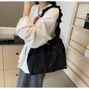 Detail of black nylon tote bag with silver studs and ruffled shoulder strap design