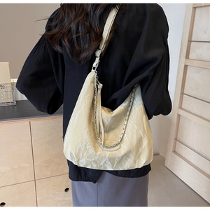 Detail view showing a cream white pleated PU leather bag with chain on a model