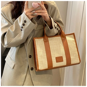 Close-up of woven straw tote bag featuring brown leather trim and CHAOHUO BAG logo patch