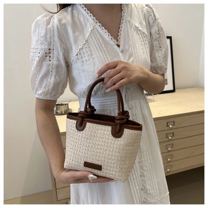 Détail du sac à main en paille tressée avec poignées en cuir marron et texture
