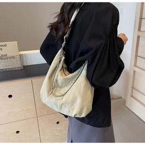 Detail of cream PU leather shoulder bag featuring pleated texture and metal chain strap