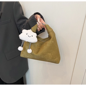Close-up of olive green suede shoulder bag with a cute white plush cloud charm accessory