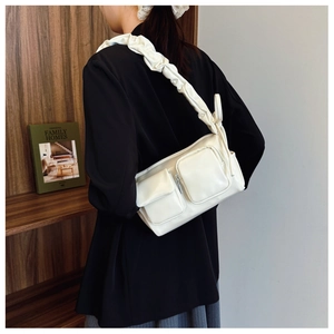 Close-up of creamy white PU shoulder bag featuring dual front pockets and pleated handle