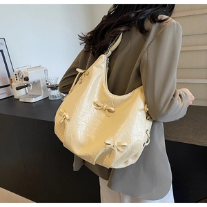 Detail shot of cream ruffled tote bag with ribbon bows and soft pleated leather texture