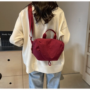 Detail of burgundy crossbody bag with nylon texture and comfortable wide strap