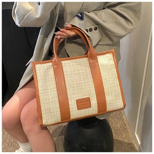 Detail of summer woven tote bag with brown leather trim and top handles on model