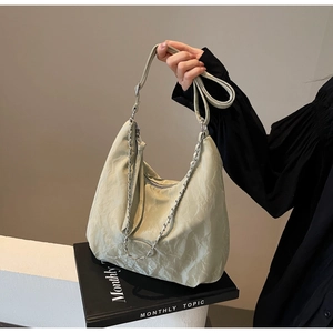 Detail of light green ruched PU leather crossbody bag with silver chain and strap