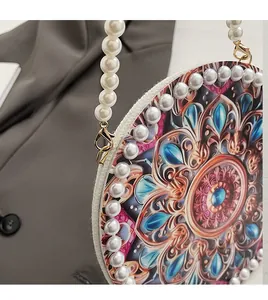 Close-up of detachable pearl handle and gold metal hook on round printed handbag