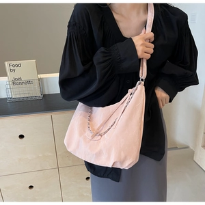 Detail of light pink PU leather shoulder bag with chain strap on female model