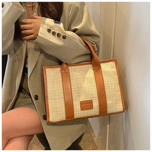 Detail view of woven fabric texture and brown leather logo on summer straw tote bag