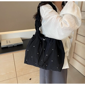 Detail of black polka dot tote bag with drawstring closure and ruffled shoulder strap
