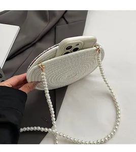 Detail of round woven bag interior with pearl strap, showing smartphone storage space