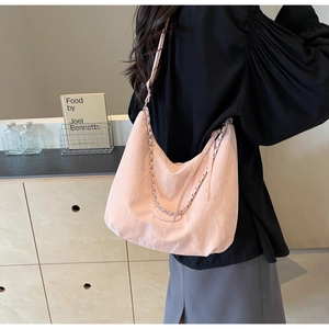 Detail of light pink pleated PU leather crossbody bag with silver metal chain on model