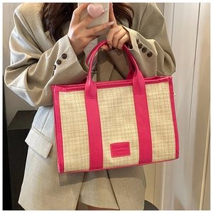Detail view of woven straw tote bag with vibrant pink PU leather trim and logo patch