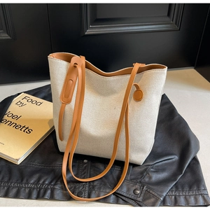 Minimalist canvas tote bag with brown leather handles on a leather jacket background