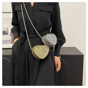 Detail of heart-shaped crossbody bags in gold and silver with sparkling rhinestones and chain