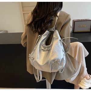 Détail du sac bandoulière en similicuir argenté avec nœud métallique et texture plissée