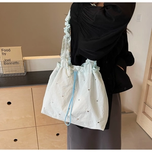 Detail of mint green handbag featuring ruffled strap and silver rivet studs detail