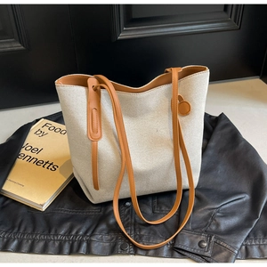 Minimalist canvas tote bag with brown leather handles placed on a black leather jacket