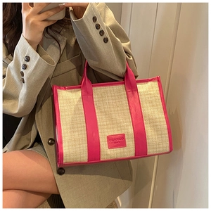 Close-up of woven straw texture and vibrant magenta faux leather trim on a tote bag