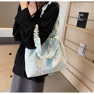 Detail of mint green ruffled shoulder bag with silver studs and light blue drawstrings