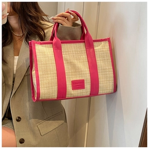 Detail of straw tote bag featuring pink faux leather trim and Chaohuo Bag logo label