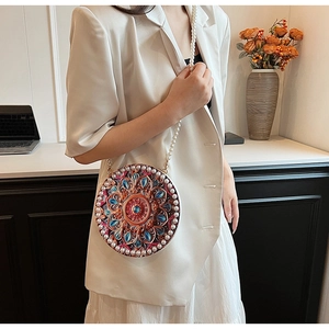 Detail of round crossbody bag with colorful mandala pattern and white pearl strap